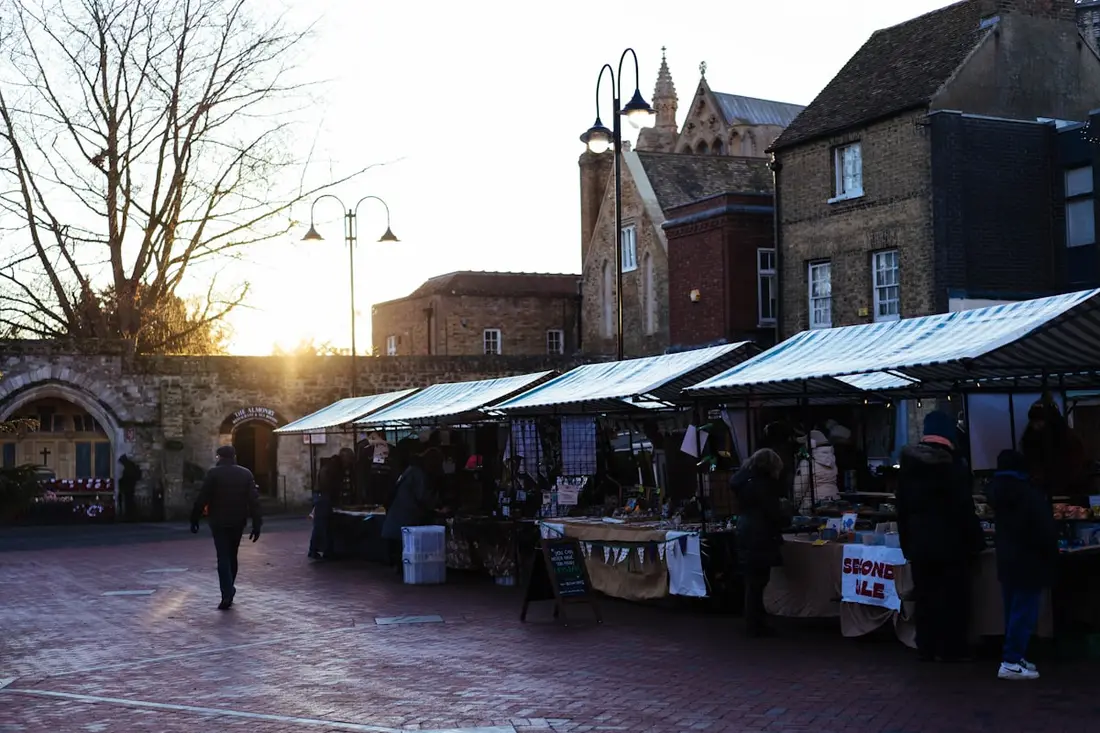 Shoppers moving between open-air market stalls