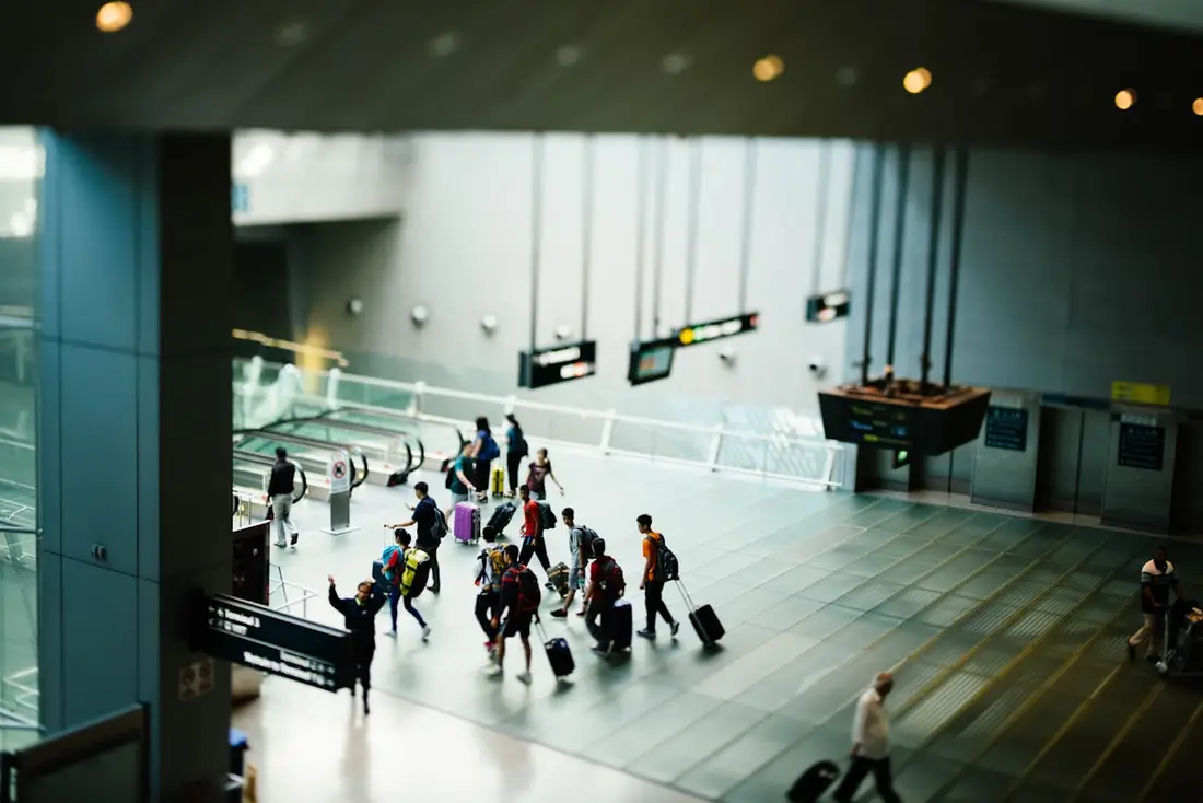 Travellers with luggage crossing a wide airport concourse